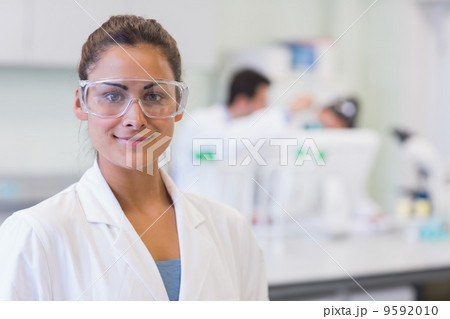 Female researcher with colleagues in background at lab 9592010
