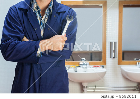 Plumber in blue boiler suit posing with wrench 9592011
