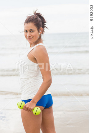 Pretty smiling sporty woman holding dumbbells smiling at camera Pretty smiling sporty woman holding dumbbells smiling at camera 9592052