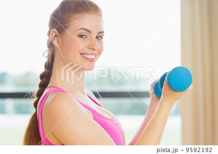 Fit woman exercising with dumbbells in fitness studio 9592192