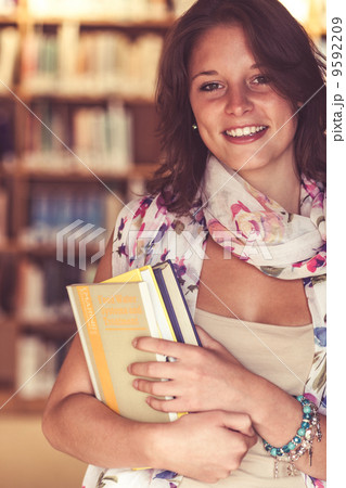 Smiling female student standing in the library Smiling female student standing in the library 9592209