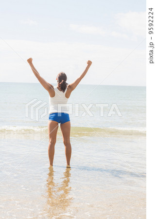 Rear view of slim young woman standing on the beach in bright su Rear view of slim young woman standing on the beach in bright su 9592224