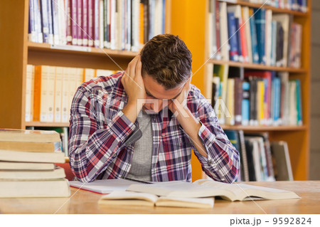 Handsome frustrated student studying his books Handsome frustrated student studying his books 9592824