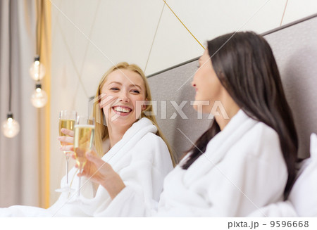smiling girlfriends with champagne glasses in bed smiling girlfriends with champagne glasses in bed 9596668