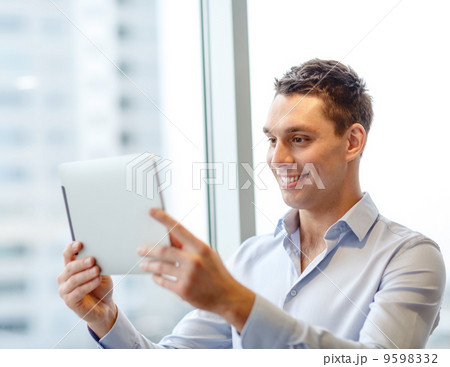smiling businessman with tablet pc in office 9598332