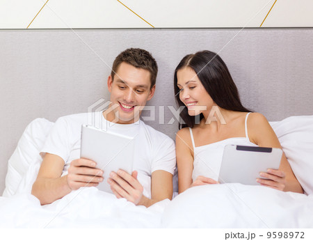 smiling couple in bed with tablet pc computers 9598972