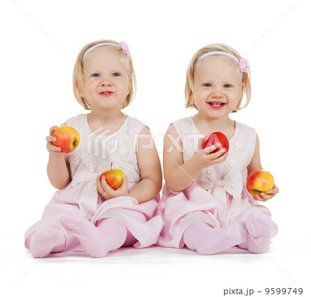 two identical twin girls playing with apples two identical twin girls playing with apples 9599749