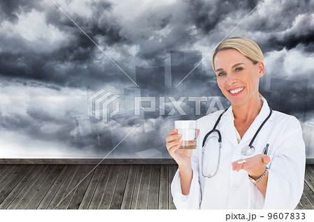 Composite image of happy doctor holding out pills and water glas 9607833