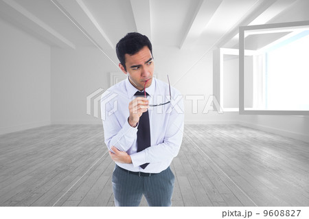 Composite image of thinking businessman holding glasses Composite image of thinking businessman holding glasses 9608827
