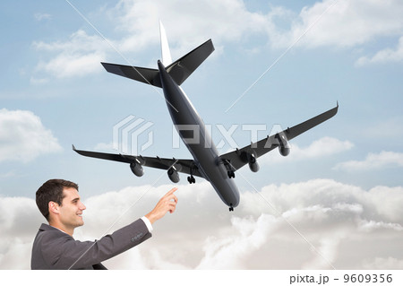 Composite image of smiling classy businessman sitting and pointi 9609356