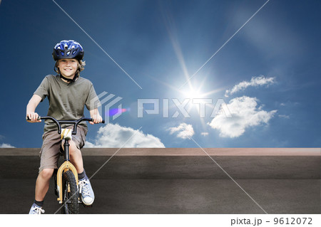 Composite image of little boy with his bike in a park 9612072