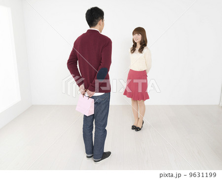 プレゼントの入ったピンク色のオシャレな紙袋を受け渡しする若い男女 9631199