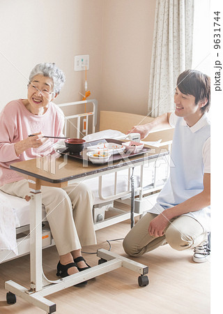 食事をする高齢の女性を見守る男性の介護士 食事をする高齢の女性を見守る男性の介護士 9631744