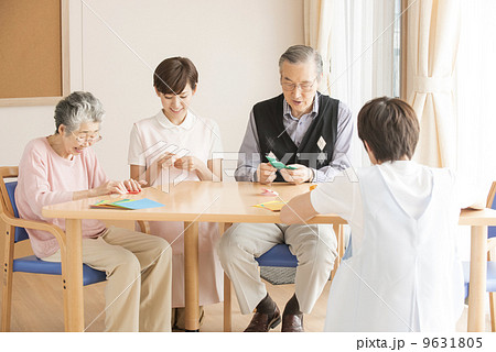 折り紙を楽しむシニアと介護士 9631805