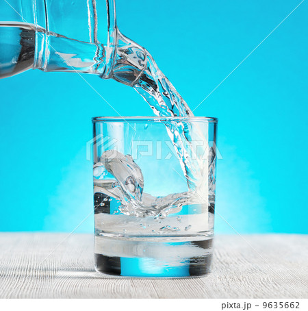 Water pouring into a glass on blue background Water pouring into a glass on blue background 9635662
