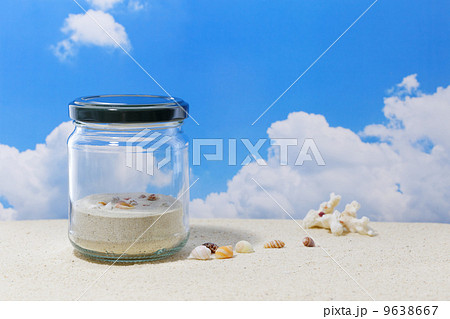 砂浜に貝殻と瓶の器の写真素材