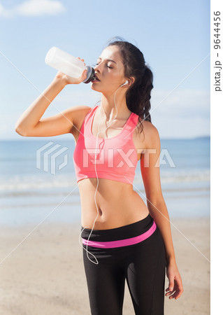 Beautiful healthy woman drinking water on beach Beautiful healthy woman drinking water on beach 9644456