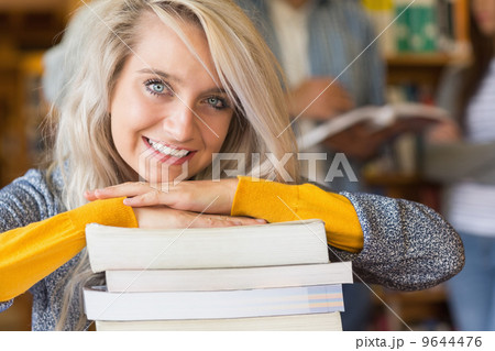 Female student with stack of books while others in background at Female student with stack of books while others in background at 9644476