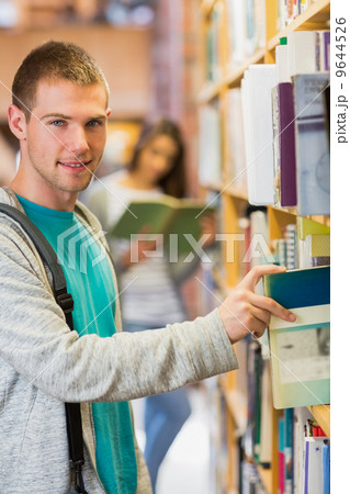 Student selecting a book from bookshelf in the library 9644526