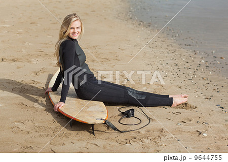 Portrait of a blond in wet suit with surfboard at beach 9644755