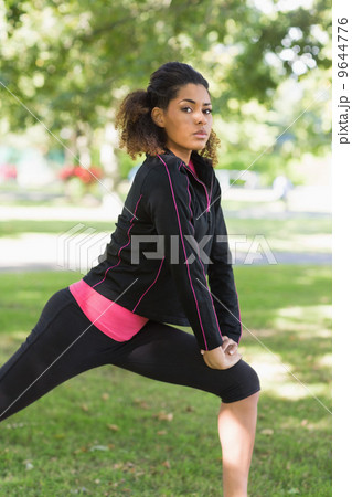 Serious healthy woman doing stretching exercise in park 9644776