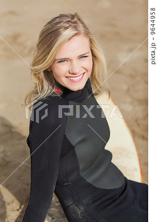 Portrait of a beautiful blond in wet suit with surfboard 9644958