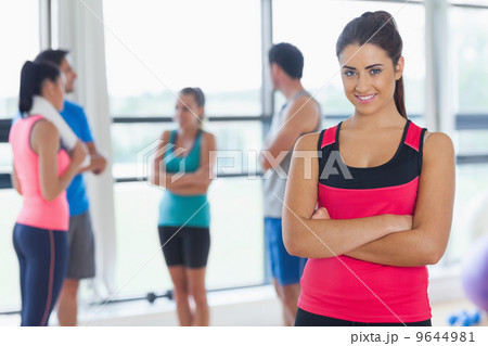 Instructor with fitness class in background in fitness studio 9644981