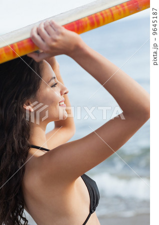 Bikini woman holding surfboard over head at beach Bikini woman holding surfboard over head at beach 9645187