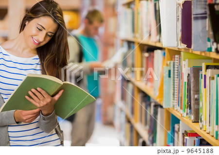 Two young students by bookshelf in the library Two young students by bookshelf in the library 9645188