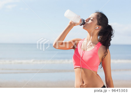 Beautiful healthy woman drinking water on beach Beautiful healthy woman drinking water on beach 9645303