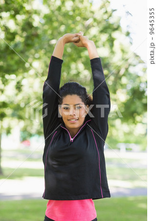 Healthy woman stretching her hands during exercise at park 9645355
