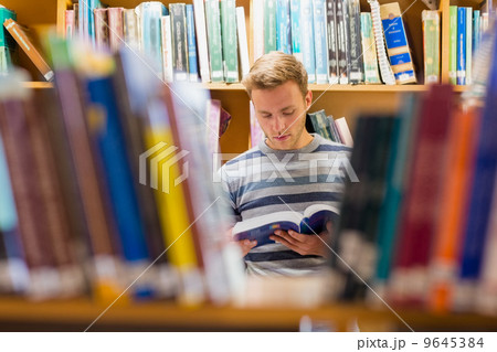 Male student reading a book in the library 9645384