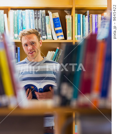 Male student reading a book in the library 9645422