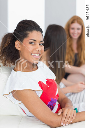 Portrait of a woman with young female friends chatting on sofa 9645486