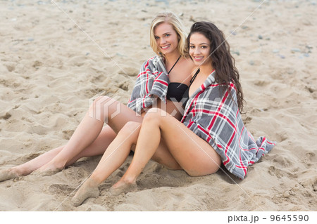 Young women covered with blanket at beach 9645590