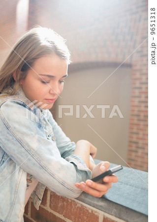 Cheerful student standing in the hall sending a text message 9651318
