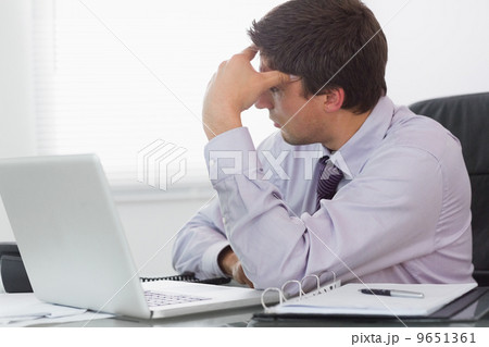 Worried businessman with laptop sitting in office 9651361
