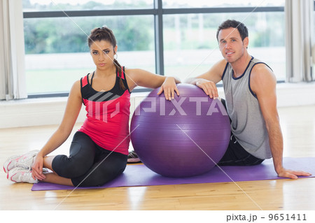 Young woman and man with fitness ball sitting at gym 9651411