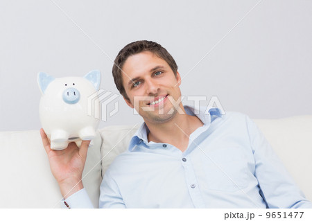 Handsome casual man with piggy bank in living room 9651477