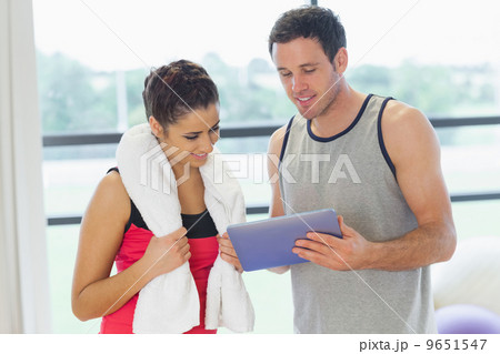 Fit couple looking at digital table in exercise room 9651547