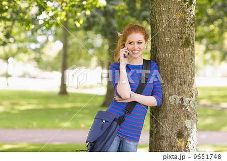 Happy student leaning against a tree talking on the phone Happy student leaning against a tree talking on the phone 9651748