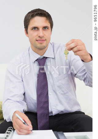 Businessman with documents holding up keys Businessman with documents holding up keys 9651796