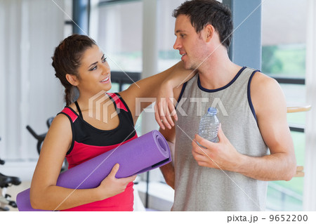 Fit couple with water bottle and exercise mat in exercise room 9652200