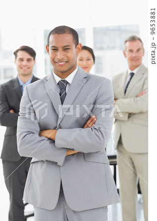 Businessman smiling at camera with team behind him Businessman smiling at camera with team behind him 9653881