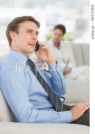 Cheerful businessman on the phone sitting on sofa Cheerful businessman on the phone sitting on sofa 9653968
