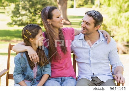 Smiling couple with daughter sitting on park bench Smiling couple with daughter sitting on park bench 9654146