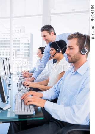 Manager and executives with headsets using computers Manager and executives with headsets using computers 9654184
