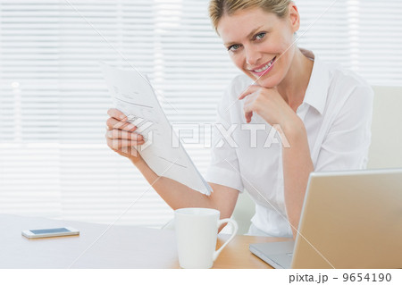 Businesswoman with laptop and document at desk Businesswoman with laptop and document at desk 9654190