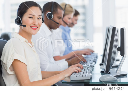 Colleagues with headsets using computers at desk Colleagues with headsets using computers at desk 9654294
