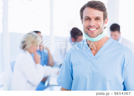 Smiling male surgeon with colleagues in meeting 9654367